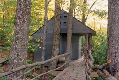 
The detached sauna, faced with flat slate recycled from Vermont classrooms, is accessible by a wooden boardwalk. The building has no foundation; the crew drilled holes and inserted stainless steel pipes into the bedrock for supports.
